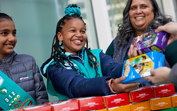 girl scout selling cookies with parent